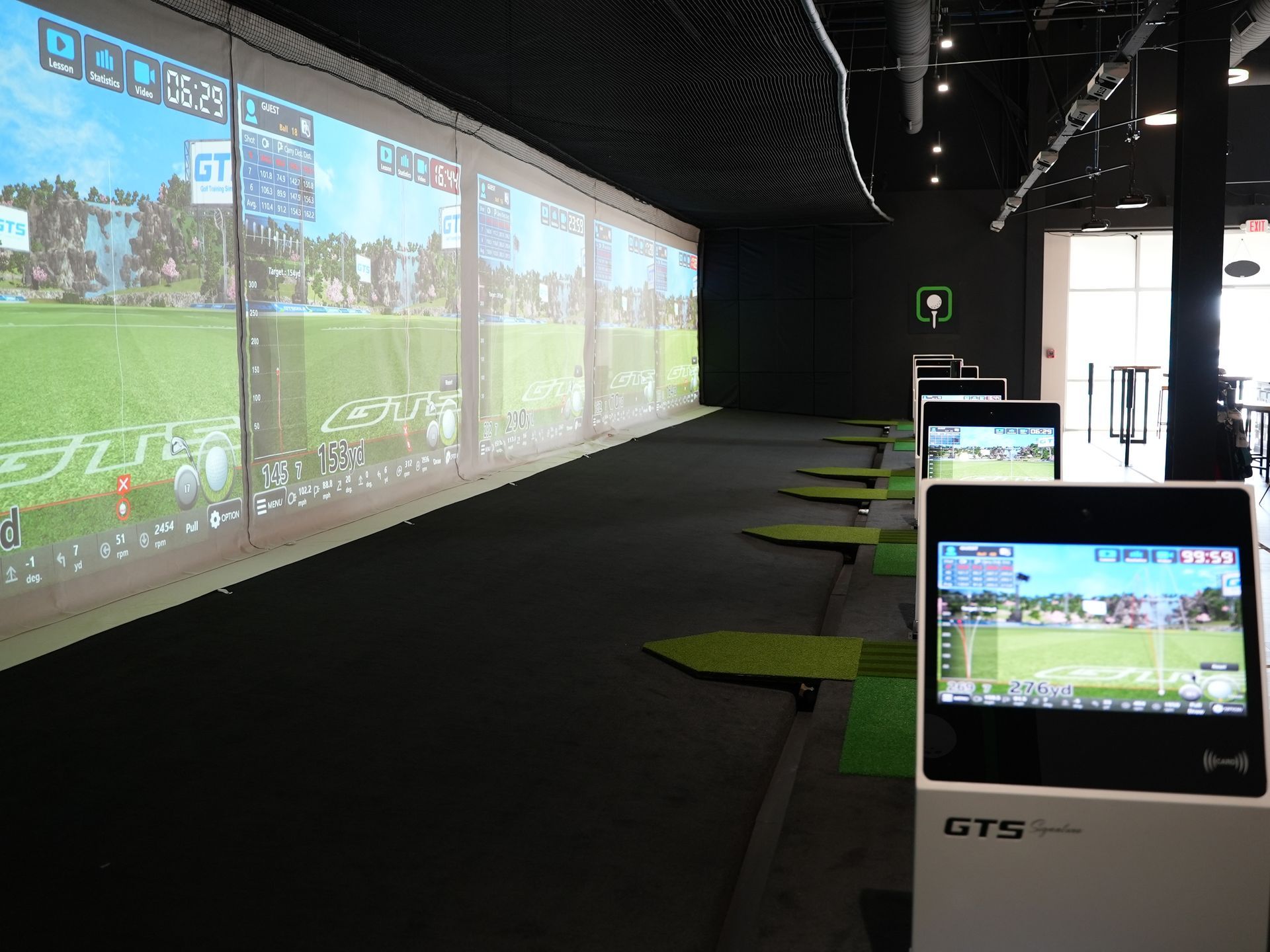 a row of golf simulators are lined up in a room
