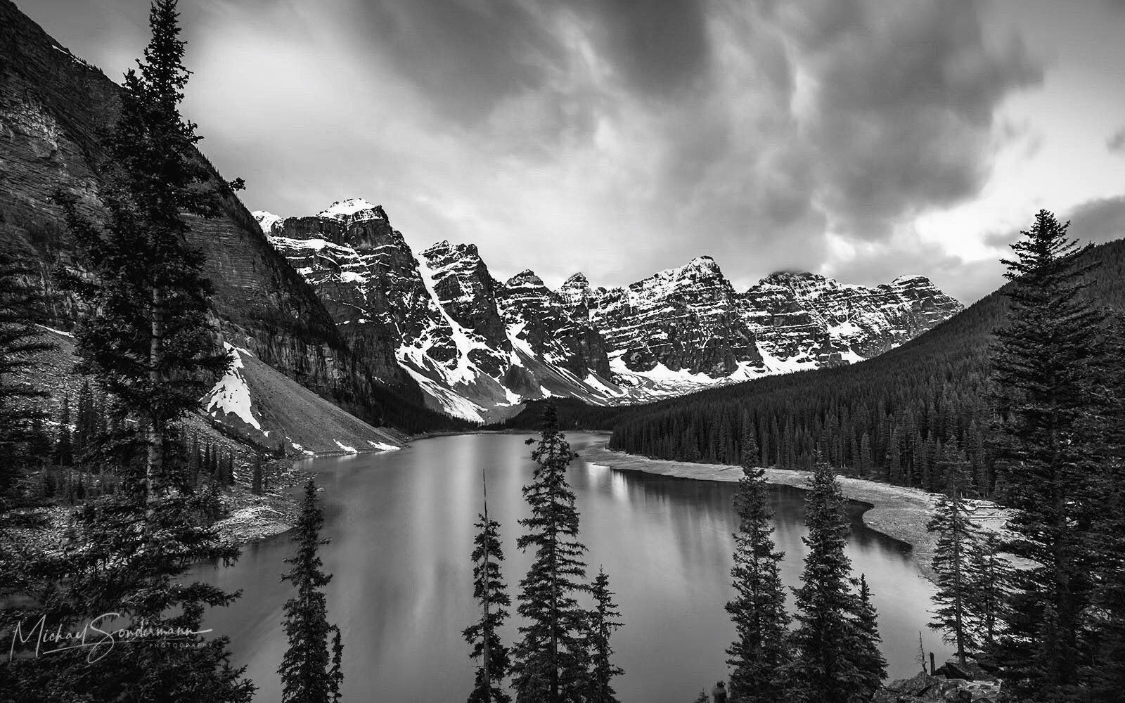 Eine schöner See in den Bergen mit Wolken am Himmel in schwarz weiss Optik.
