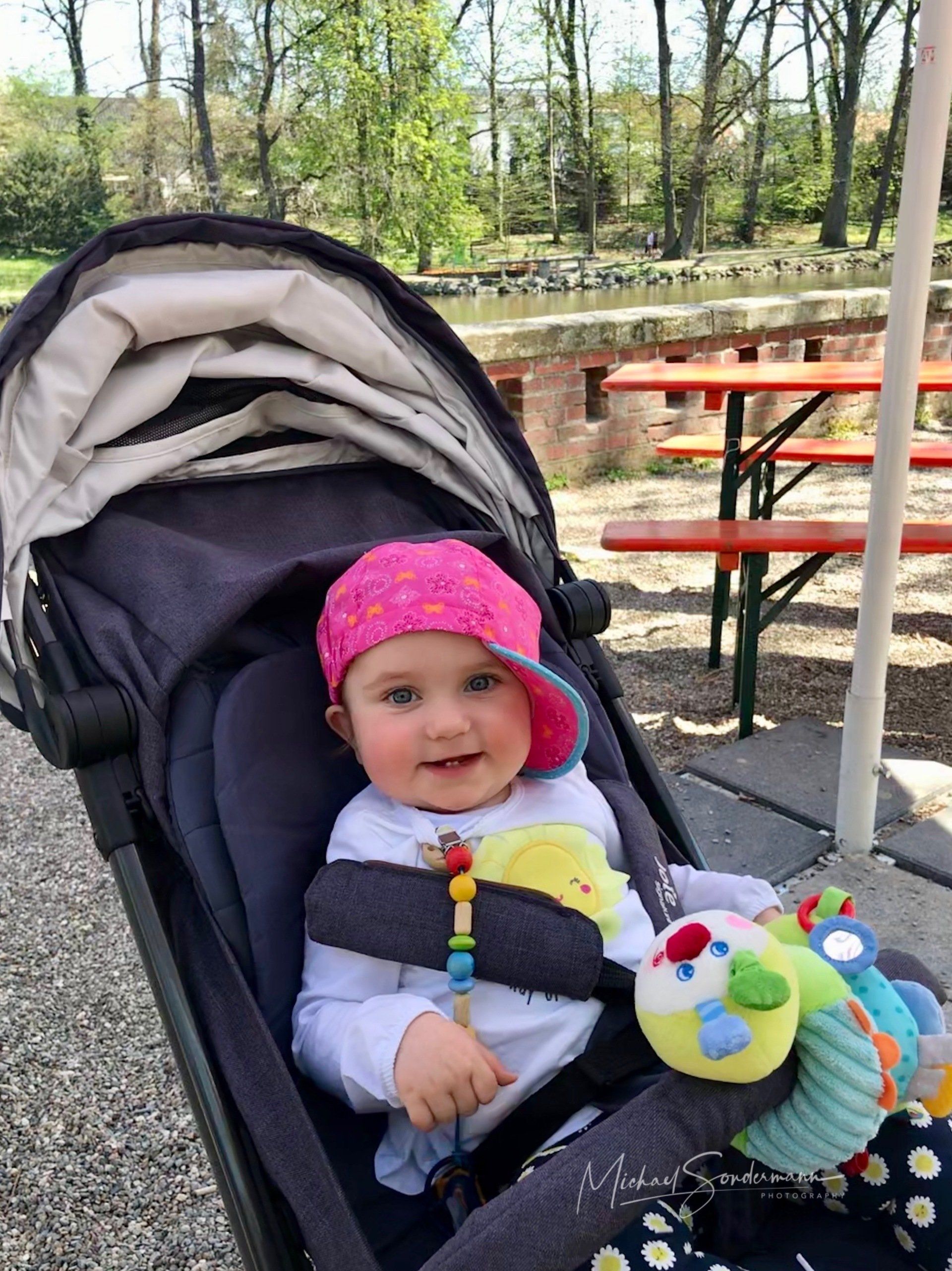 Ein junges Mädchen sitzt grinsend im Kinderwagen