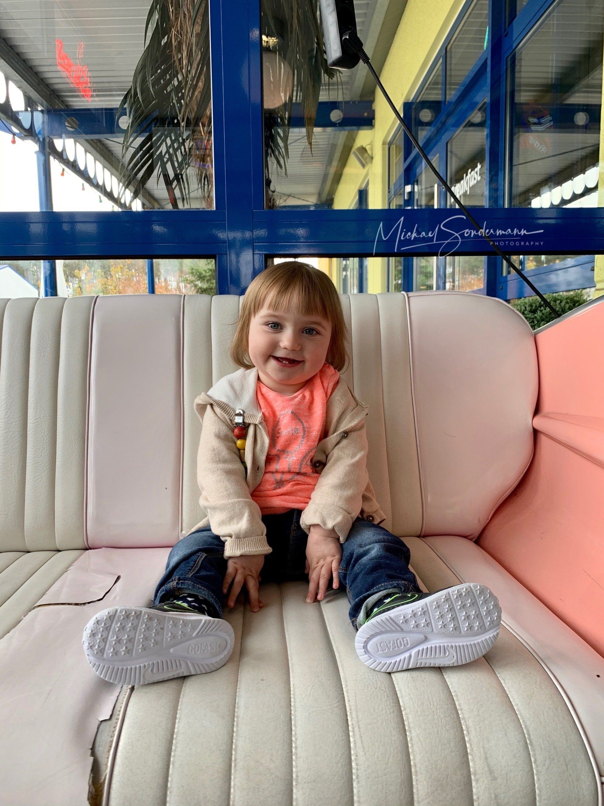 Ein junges Mädchen sitzt lachend auf einen alten amerikanischen Sofa in einen Diner.