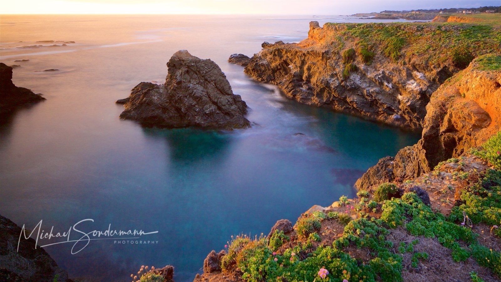 Ein Blick von der Steinküste in California auf den Pazifik herunter bei Sonnenschein.