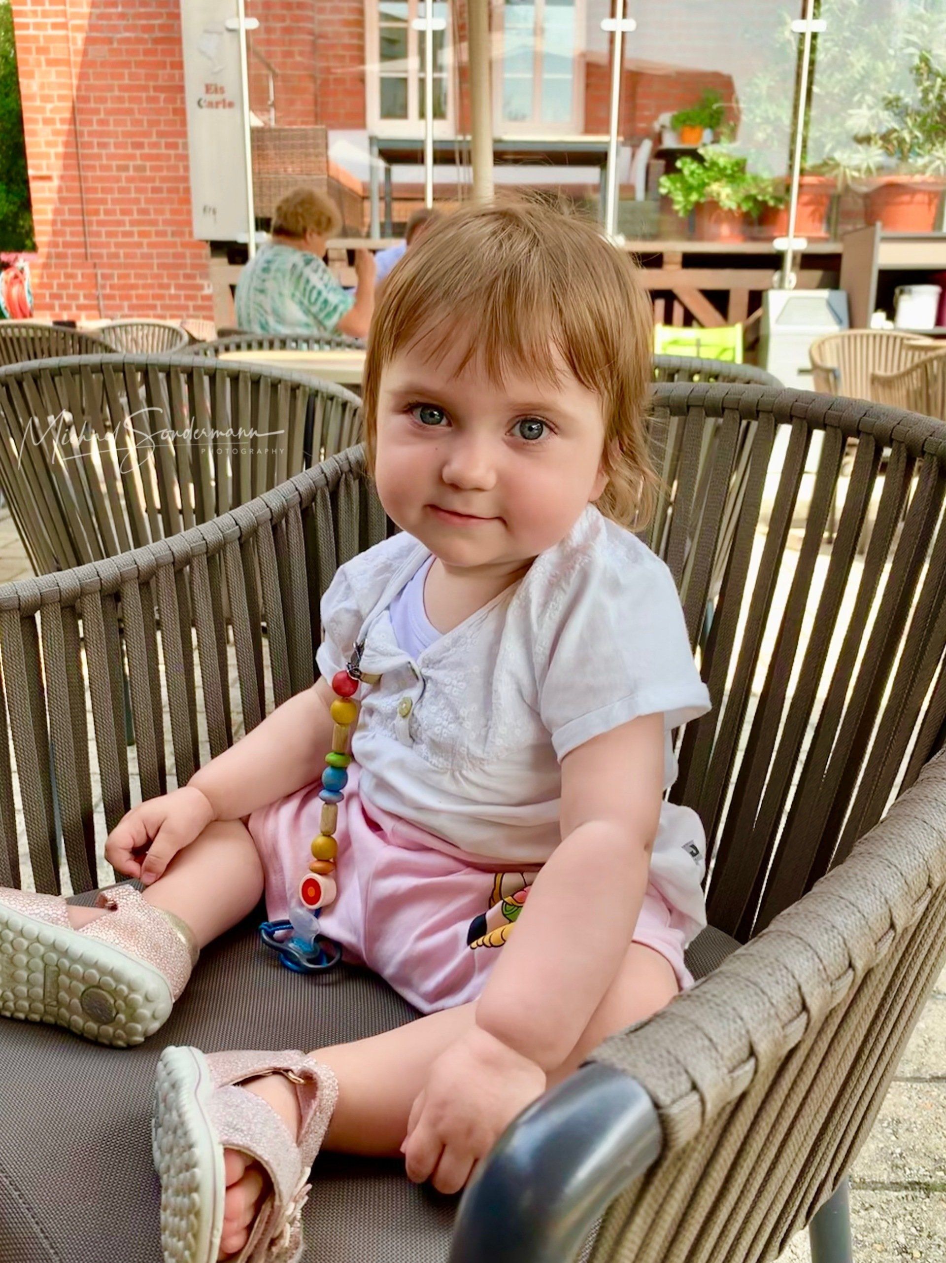 Ein junges Mädchen sitzt im Sommer auf einen Stuhl im Eiscafe.