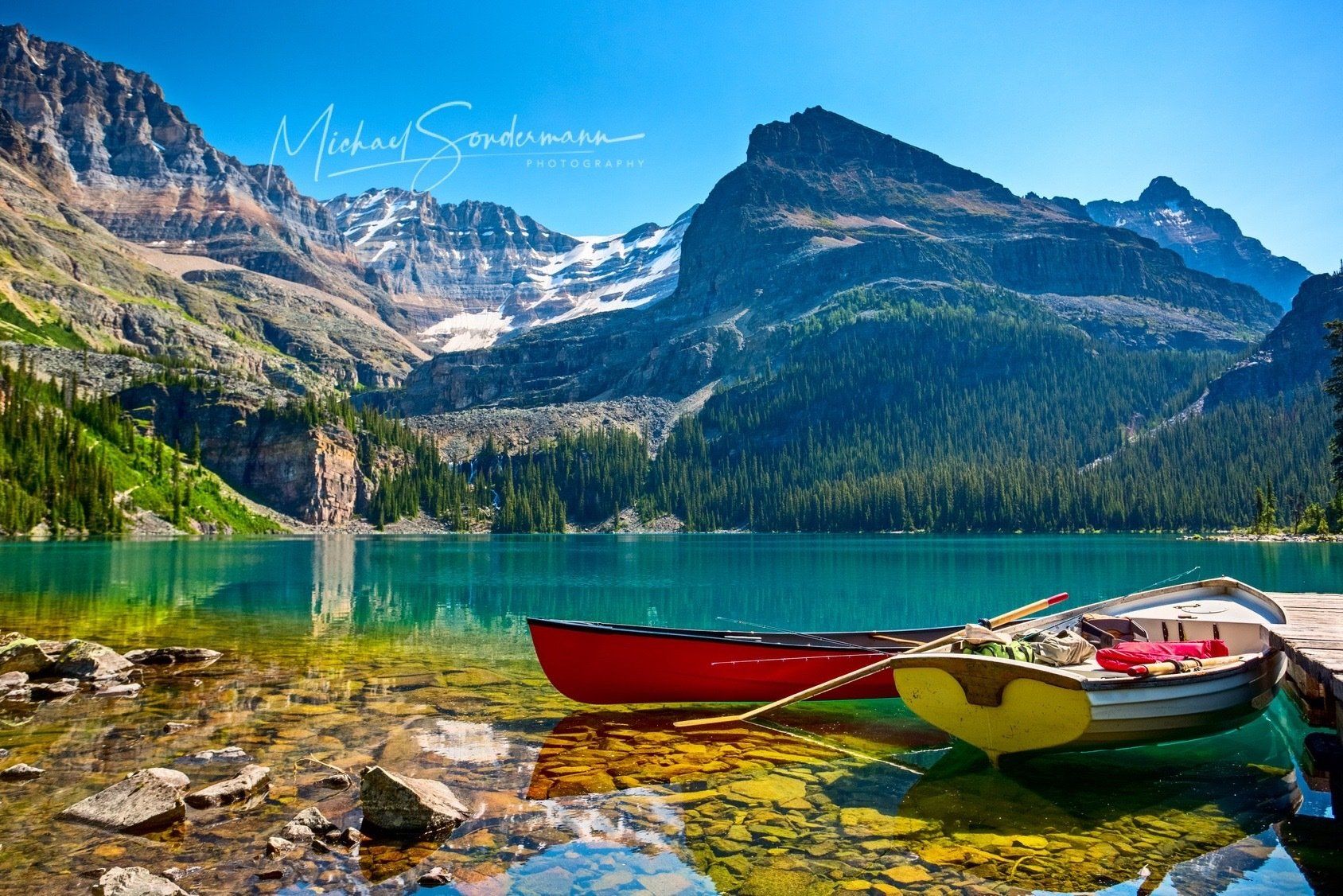 Ein Blick auf einen schönen türkisfarbenen See mit 2 Ruderboote am Strand und Berge im Hintergrund in den USA.