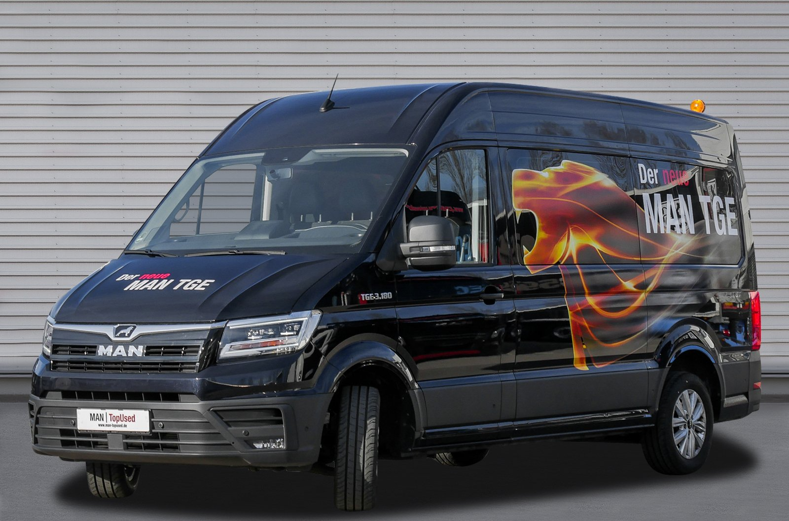 Ein schwarzer Lieferwagen mit einem Löwen an der Seite steht vor einem Gebäude.