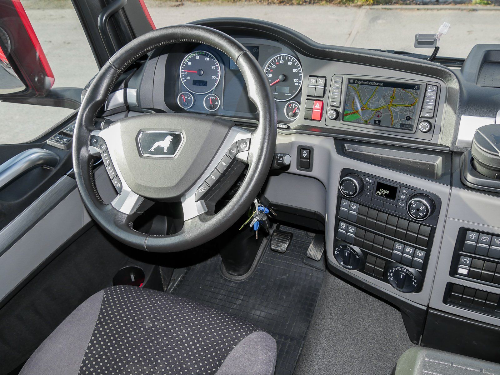 Ein großer roter 4 achsiger Truck von innen gesehen auf das Lenkrad und deren Bedienelemente.