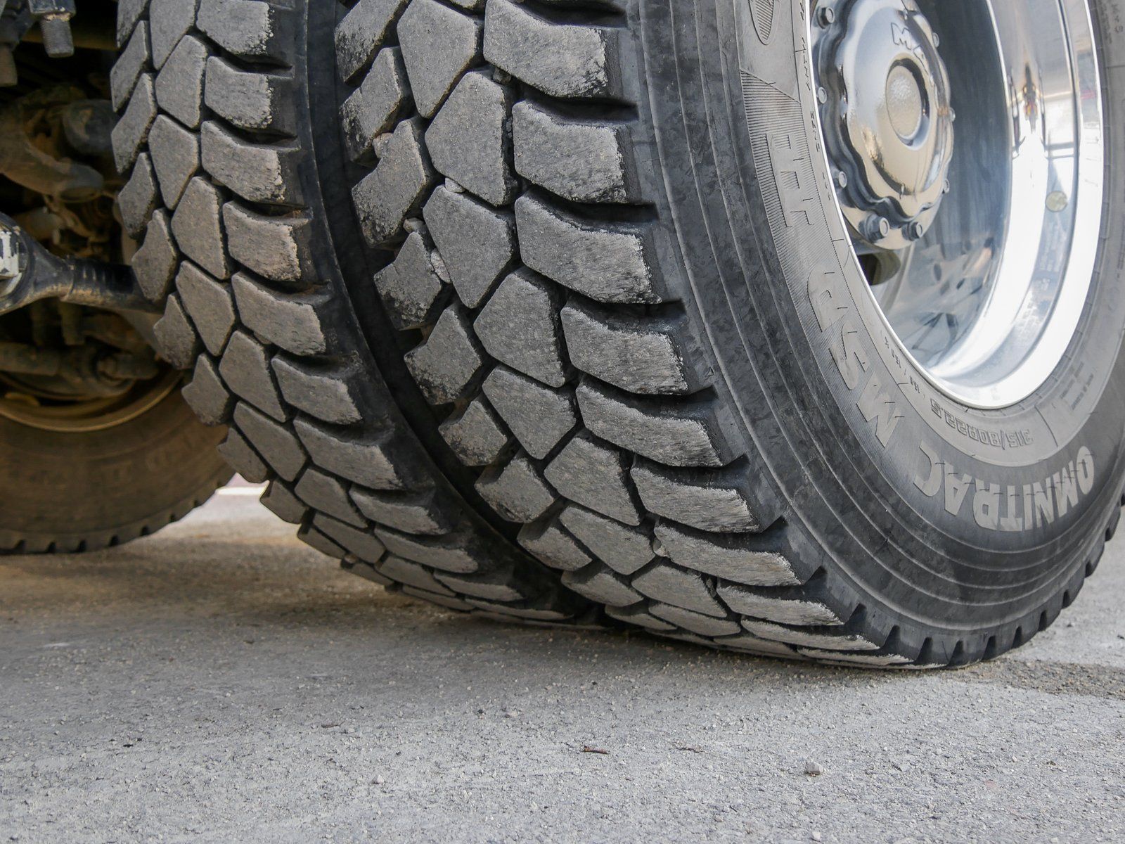 Ein großer roter 4 achsiger Truck von unten gesehen auf das Profil der Bereifung hinten links.
