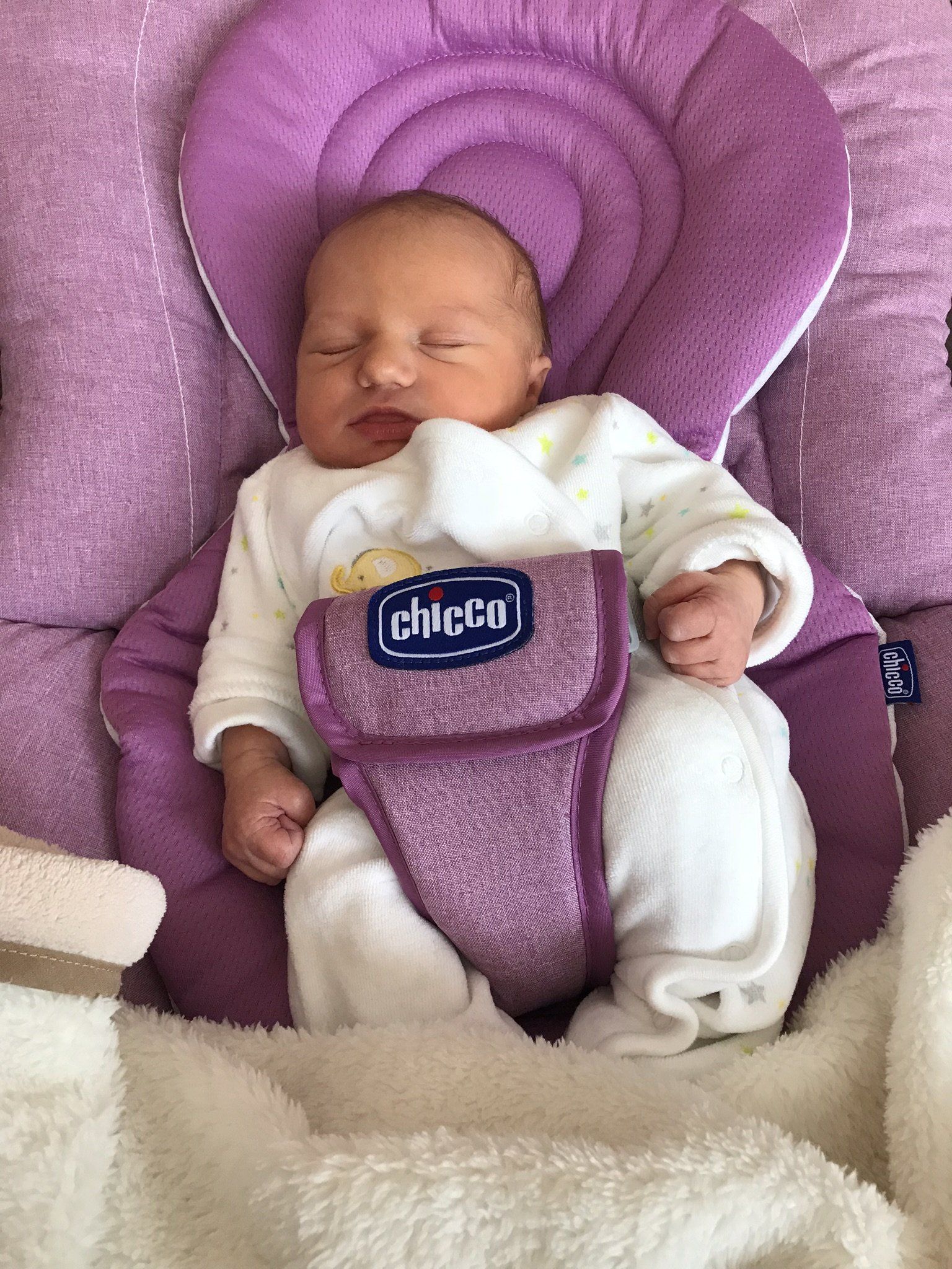 Ein Baby liegt schlafend in einer Babywippe.