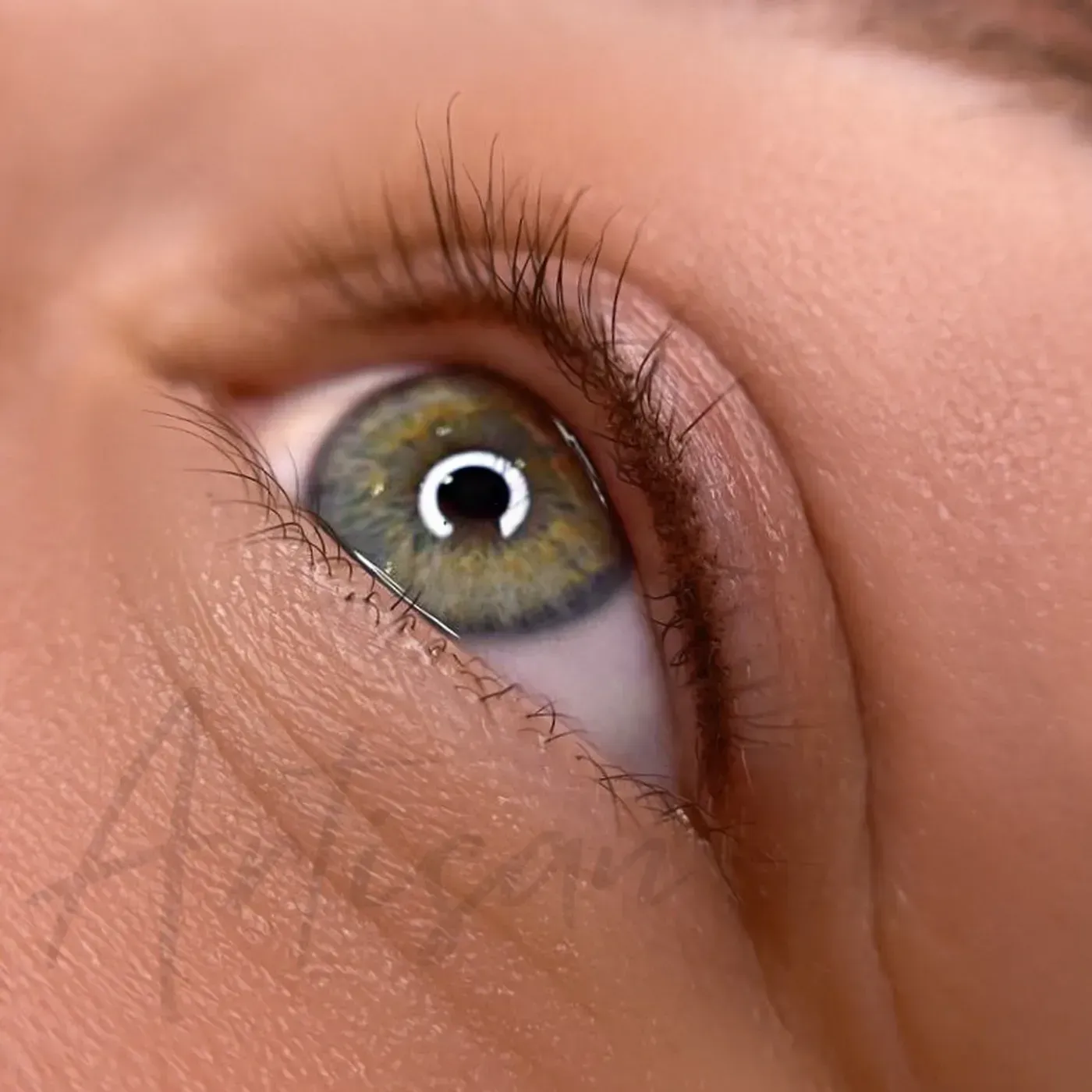 A close-up of a hazel-green eye with a fine permanent eyeliner tattoo along the upper lash line. — Artisan Cosmetic Tattoo & Beauty in Worongary, QLD