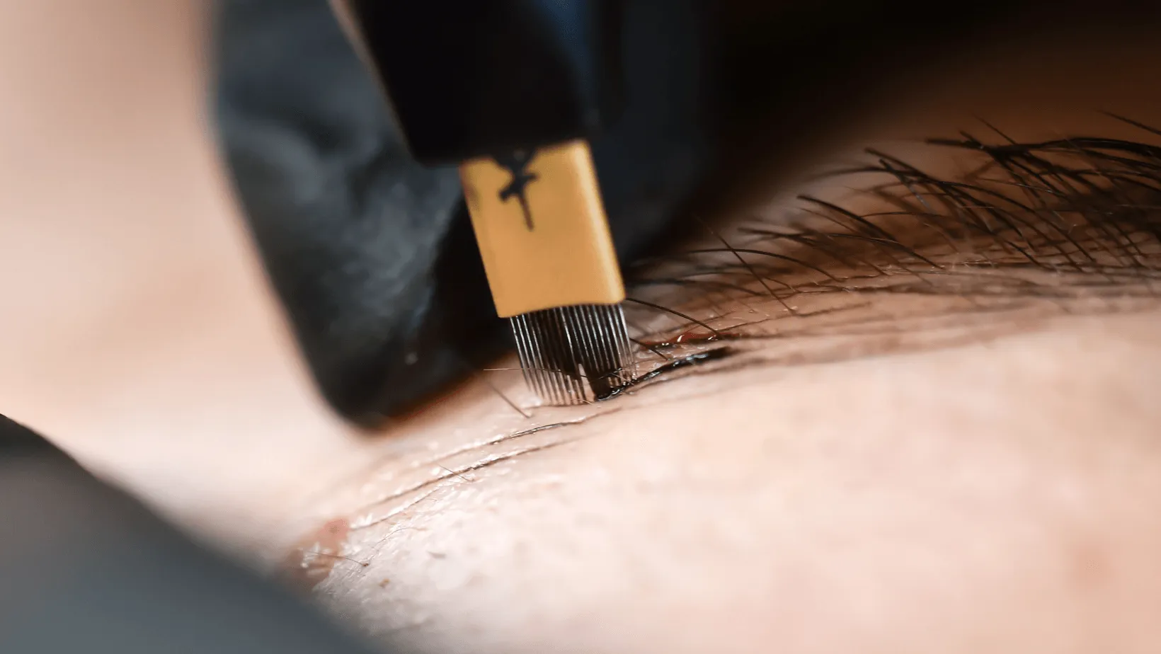 A Hand Holding a Microblading Tool, Creating Eyebrow Strokes on Skin — Artisan Cosmetic Tattoo & Beauty in Worongary, QLD