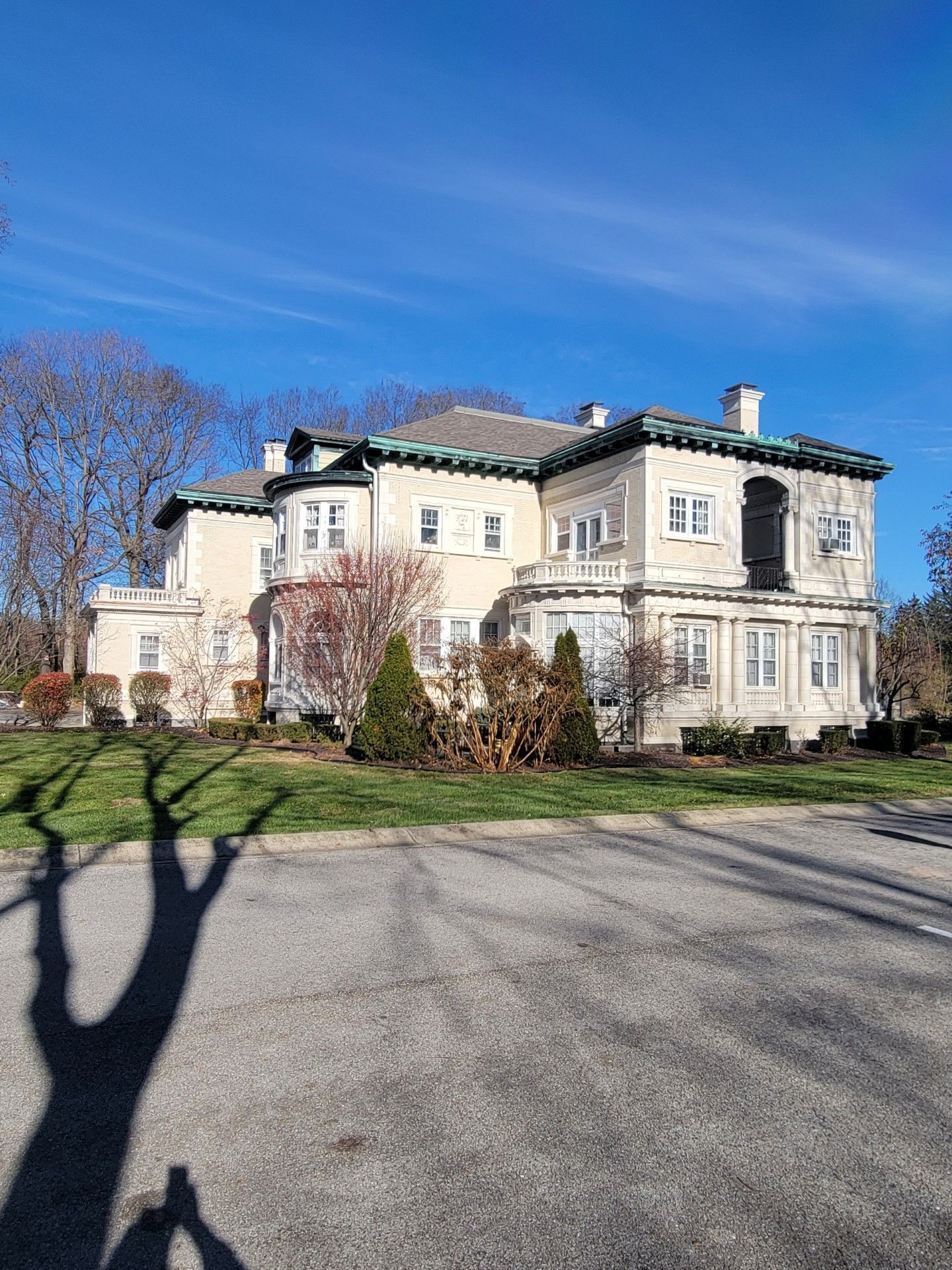 A large white house is sitting on top of a lush green hillside.