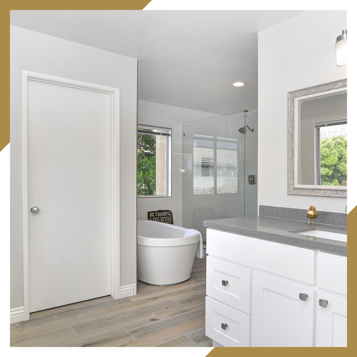 A bathroom with a tub , sink and mirror.