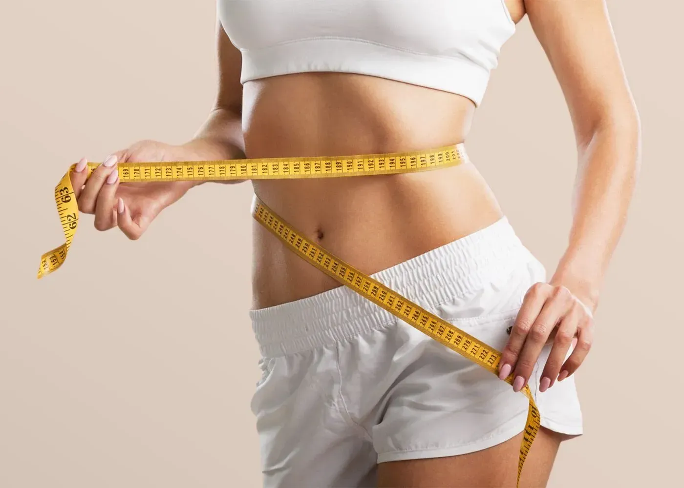 Eine Frau misst ihre Taille mit einem Maßband.