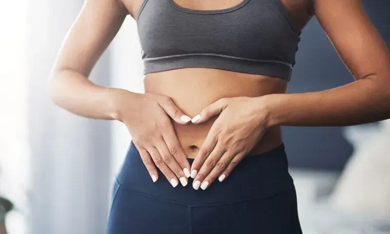 Eine Frau in einem rosa Kleid steht mit den Händen auf den Hüften vor einem Logo für QD A
