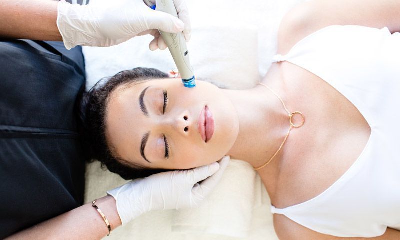 Eine Frau liegt auf einem Bett und bekommt eine Gesichtsbehandlung.