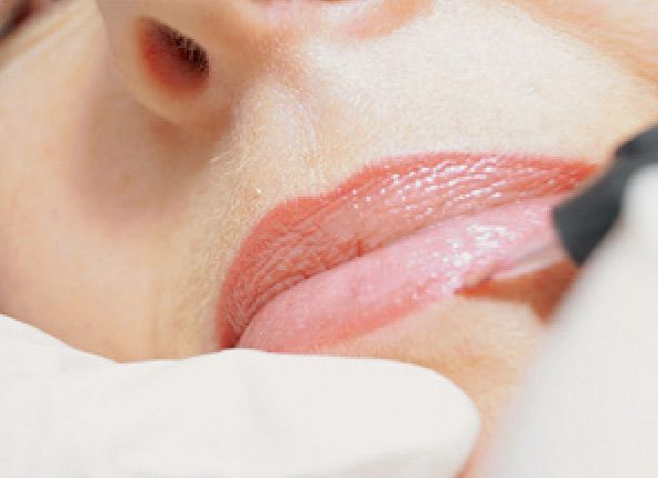 Eine Nahaufnahme der Lippen einer Frau, die mit Lippenstift bemalt werden.
