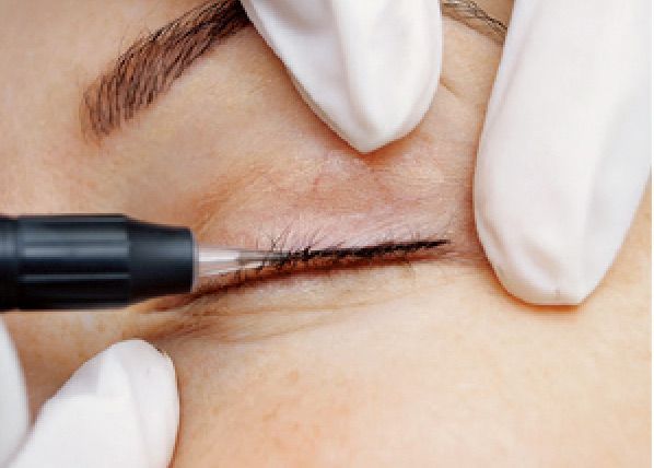 Eine Frau lässt sich mit einem Stift Eyeliner auf ihr Auge tätowieren.