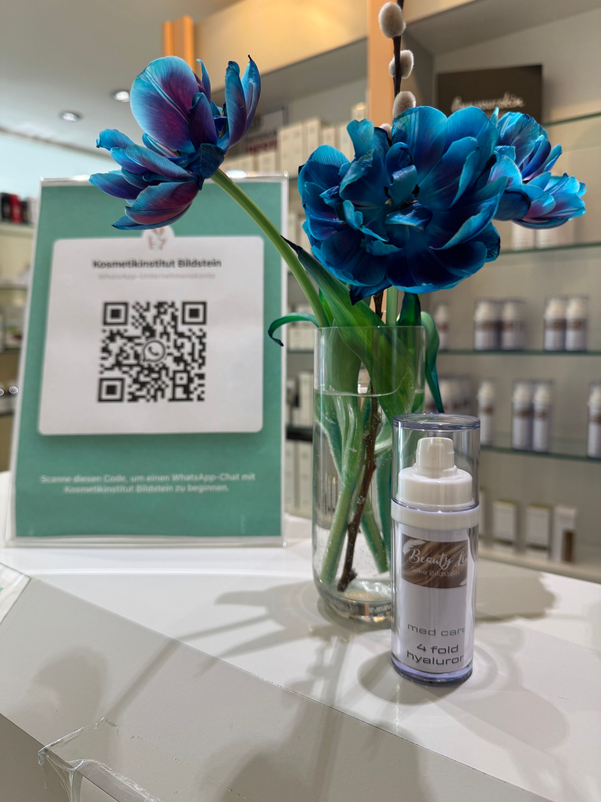 Blaue Blumen in einer Vase neben einer Flasche Lotion