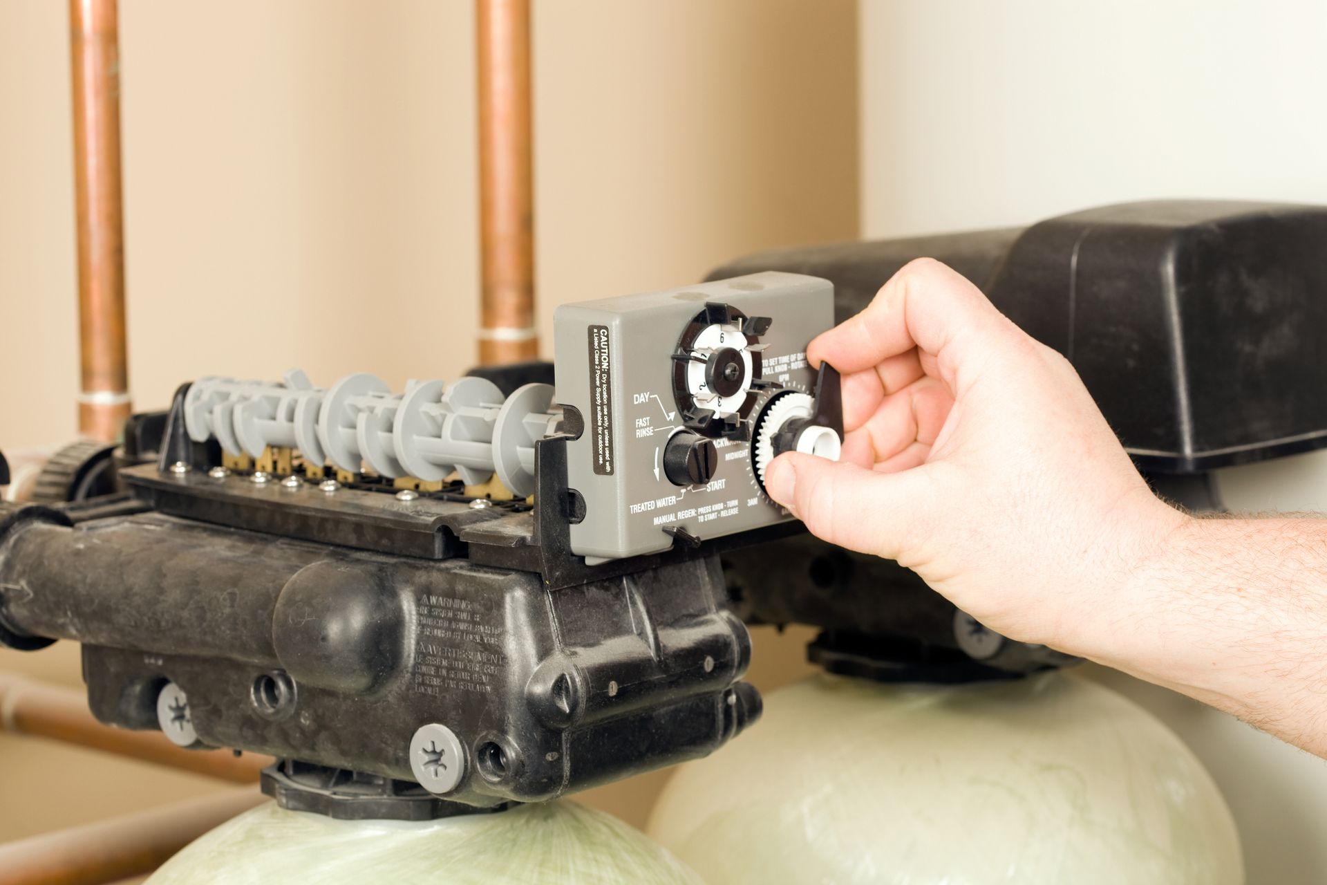 A person is adjusting a valve on a water softener.