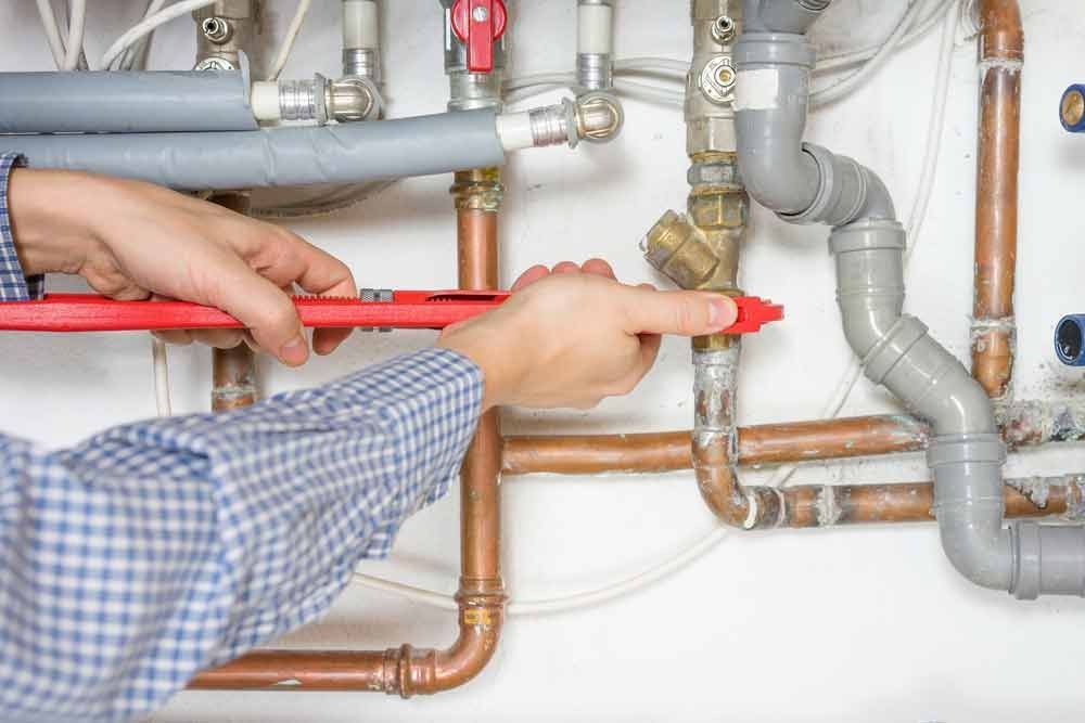 A Plumber is Fixing a Pipe With a Wrench — Tony Brown Plumbing & Gas Services in South Grafton, NSW