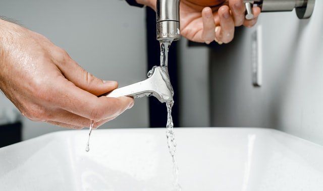 A Person is Washing a Razor in a Bathroom Sink — Tony Brown Plumbing & Gas Services in South Grafton, NSW