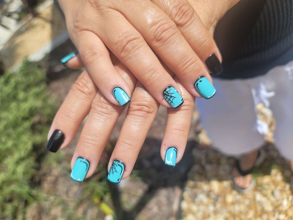 A close up of a woman 's nails with blue and black nail polish