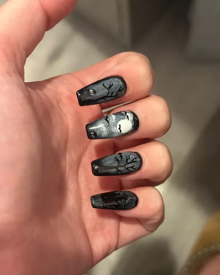 A close up of a person 's hand with black and silver nails.