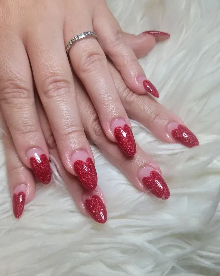 A woman 's nails are painted red and have hearts on them.