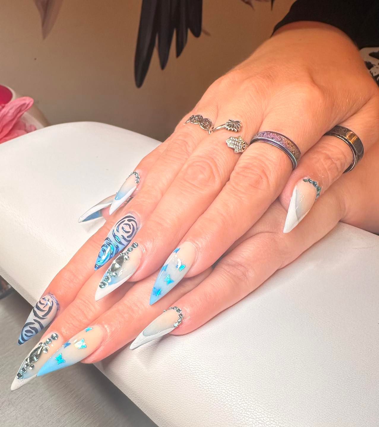 A close up of a woman 's hand with long nails and rings