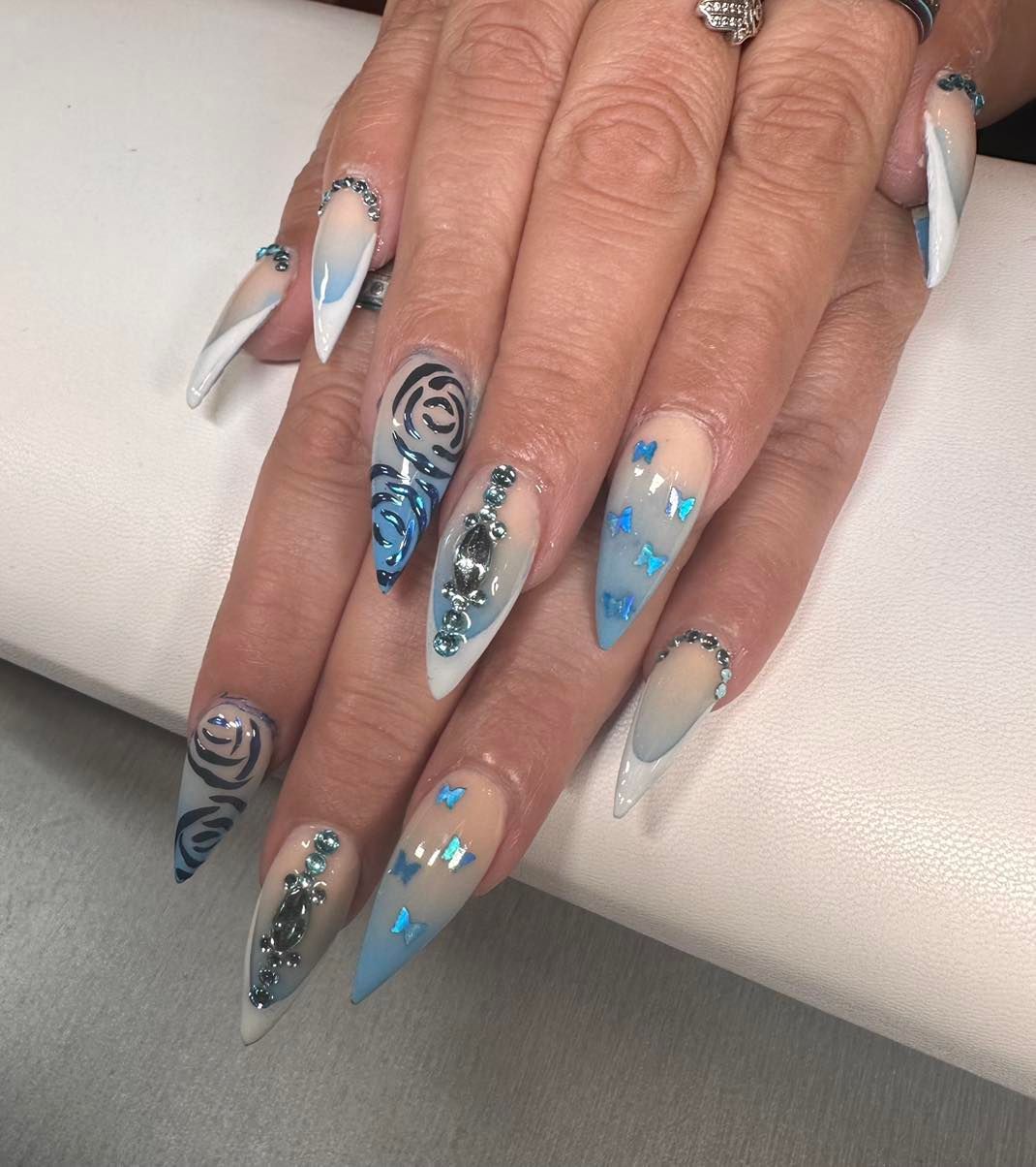 A close up of a woman 's nails with blue and white designs