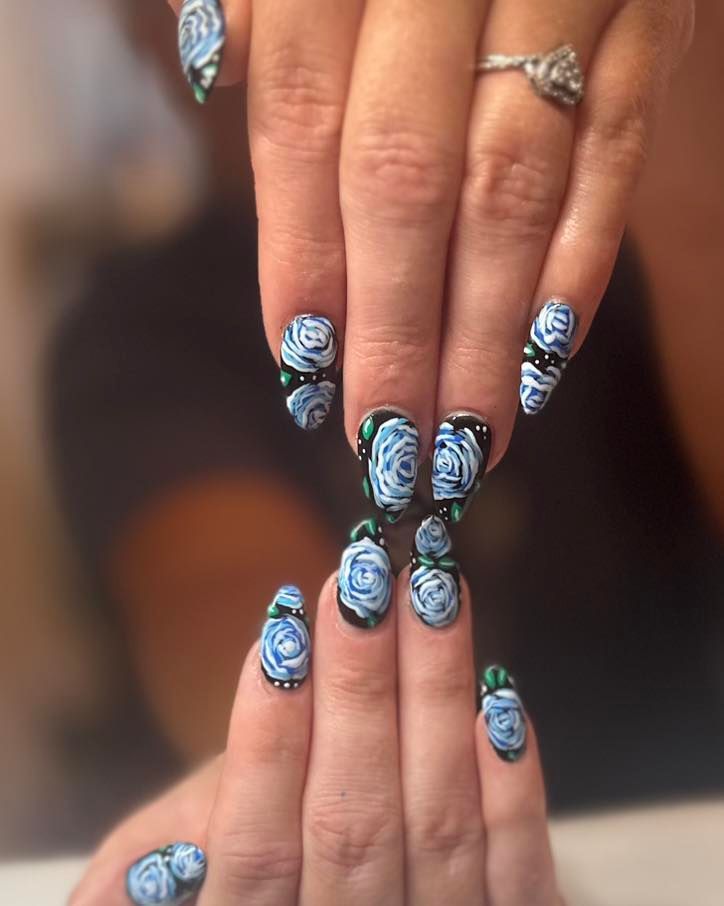 A close up of a woman 's nails with blue roses on them