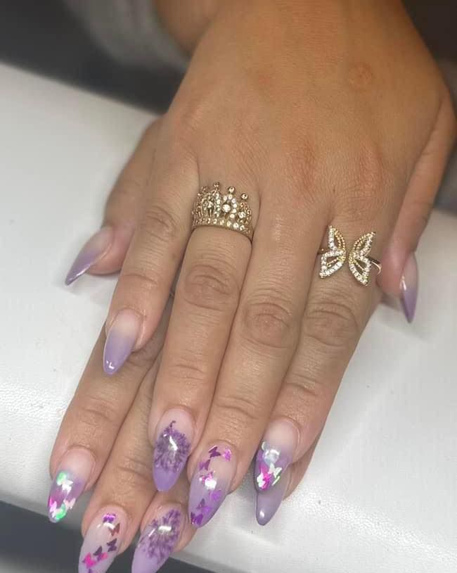 A close up of a woman 's hand with purple nails and a ring and earrings.