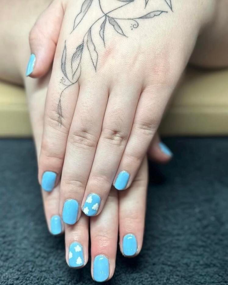 A woman 's hand with blue nails and a tattoo on her wrist.