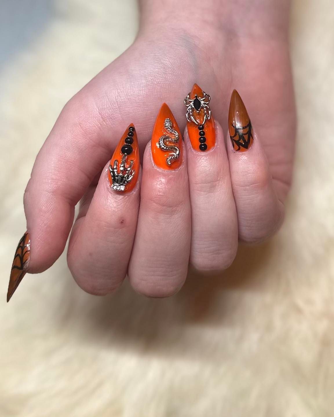 A close up of a person 's hand with orange nails