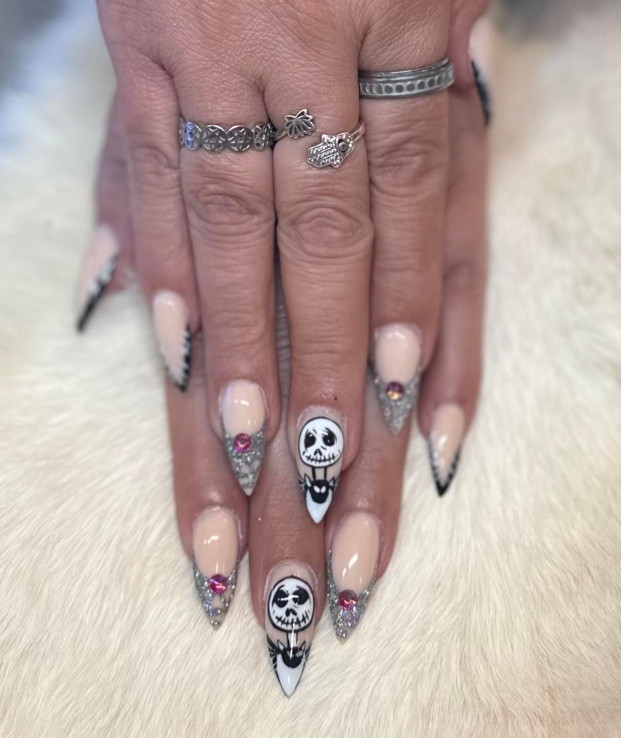 A woman 's nails are decorated with skulls and rhinestones.