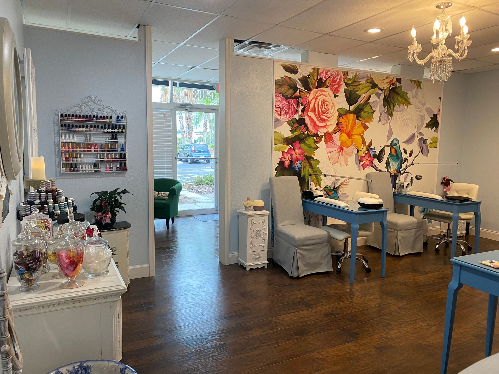 A nail salon with tables and chairs and a floral wallpaper on the wall.