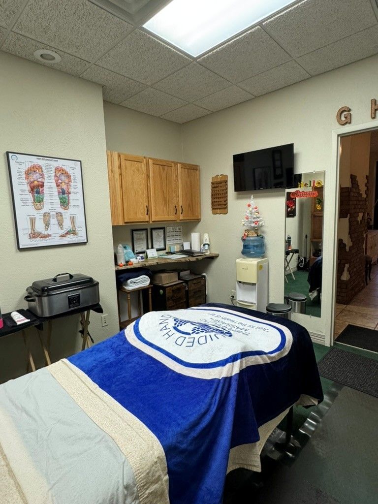 Hands massaging the sole of a foot on a white towel.