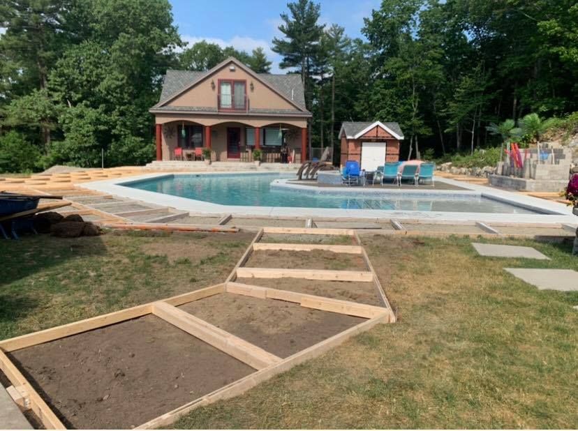 A large swimming pool is being built in the backyard of a house.