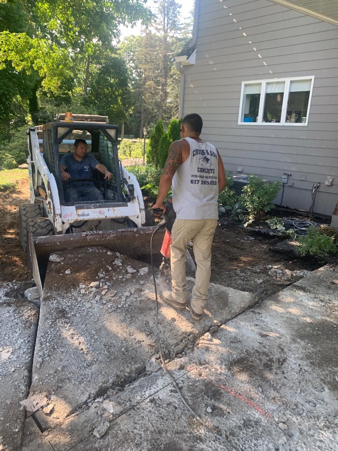 A man is standing next to a bulldozer in front of a house.