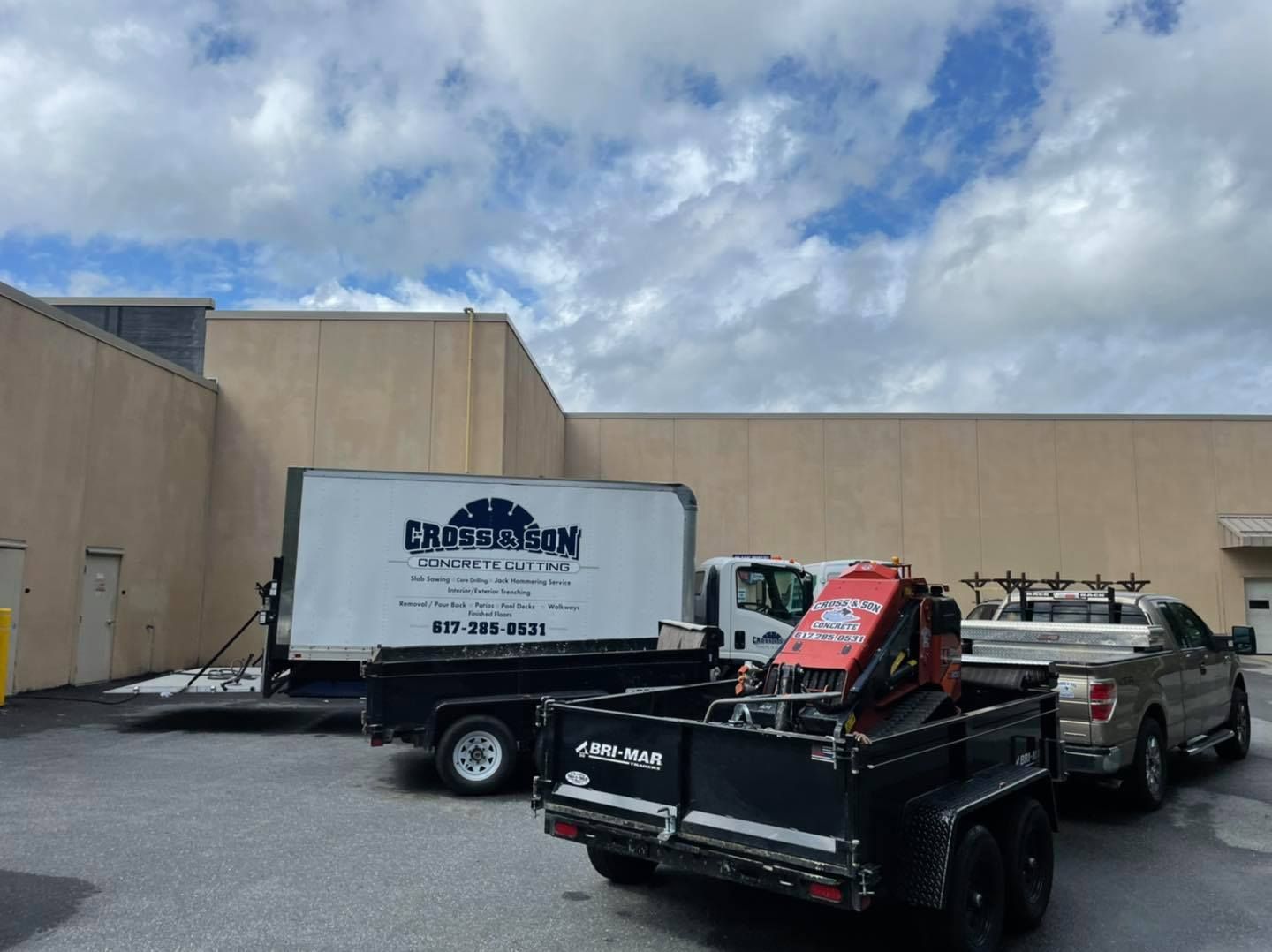 Two trucks and a trailer are parked in front of a building.