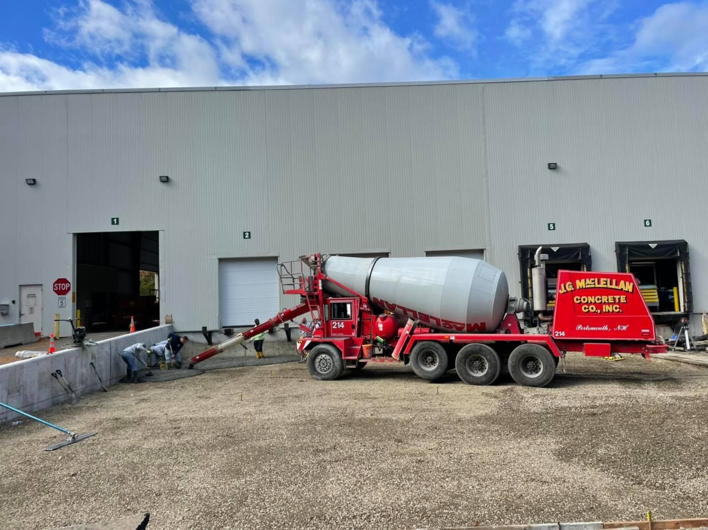 A red concrete mixer truck is parked in front of a building.