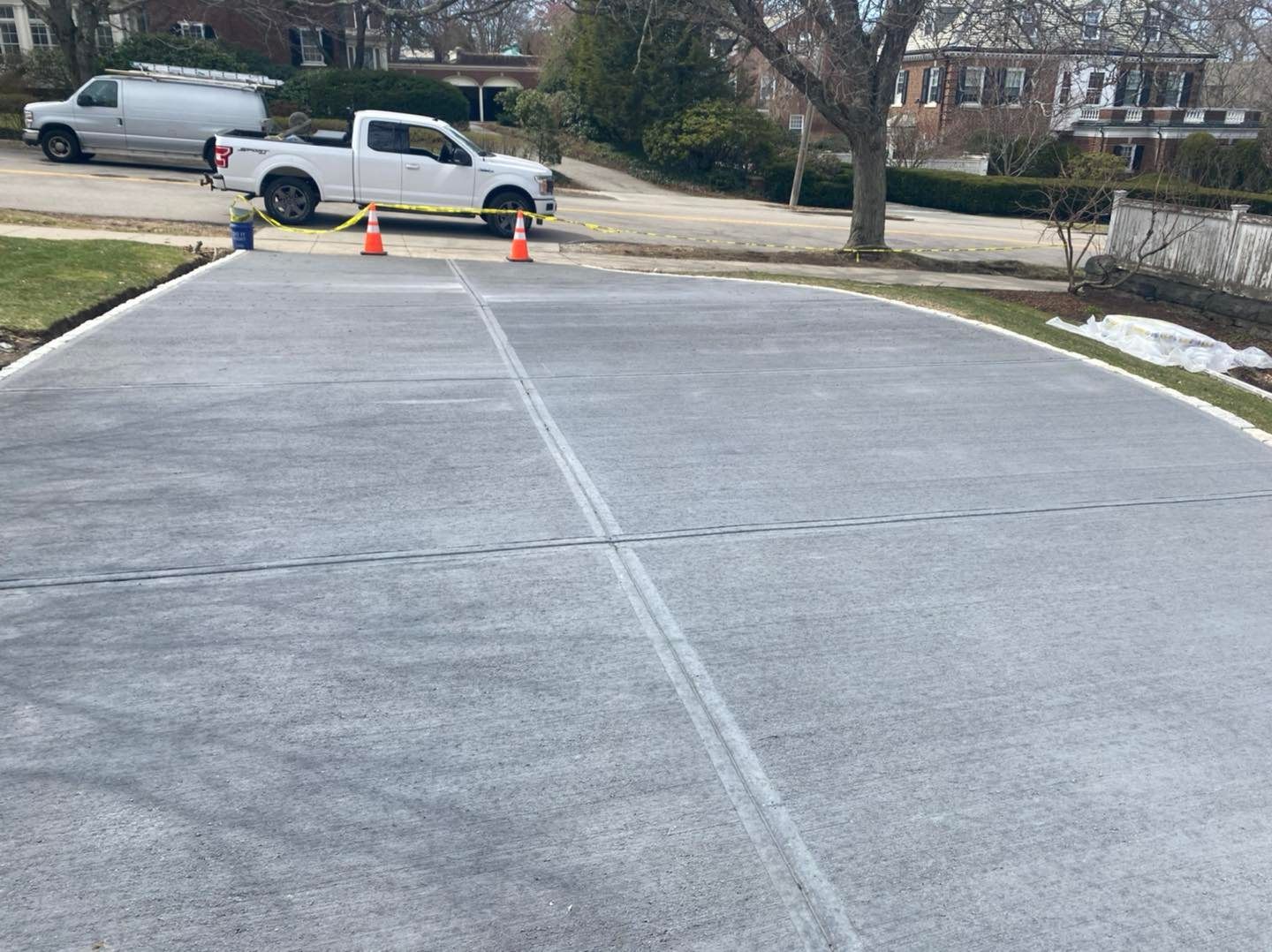 A white truck is parked on the side of a concrete driveway.