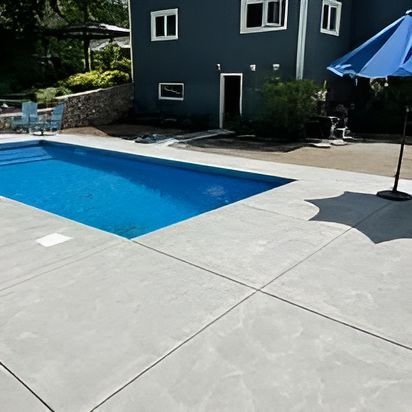 A large swimming pool with a blue umbrella in front of a house