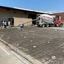 A concrete mixer truck is pouring concrete into a concrete yard.