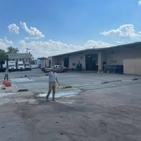 A man is standing in a parking lot next to a building.