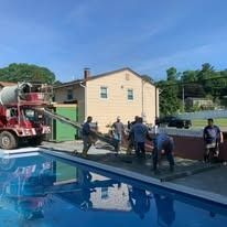 A group of people are standing next to a swimming pool.