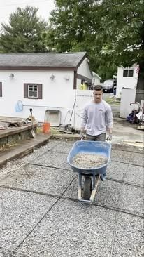 A man is pushing a wheelbarrow full of gravel.