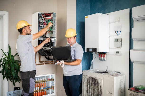 Two men are working on a heating system in a room.