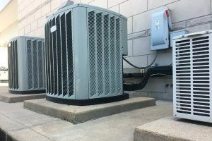 Three air conditioners are sitting on top of concrete blocks on the side of a building.