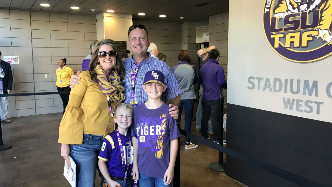 A family is posing for a picture in front of a sign that says stadium west.