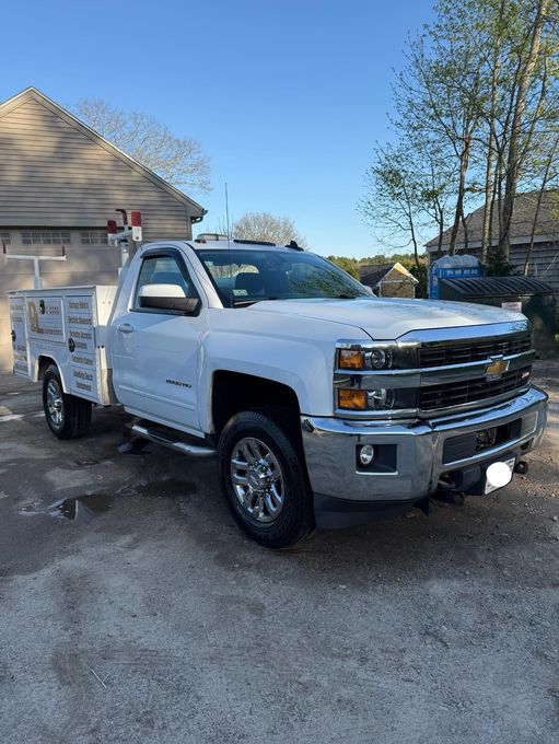 White Chevrolet work truck parked on gravel, sunny day.